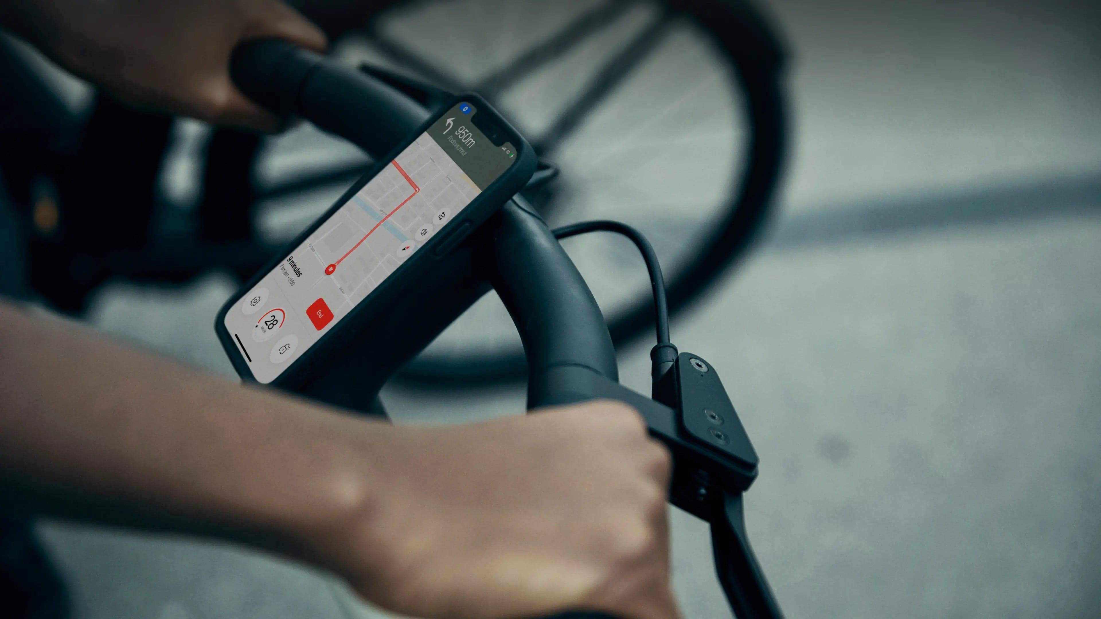 A hand on the handlebar next to a phone showing directions.